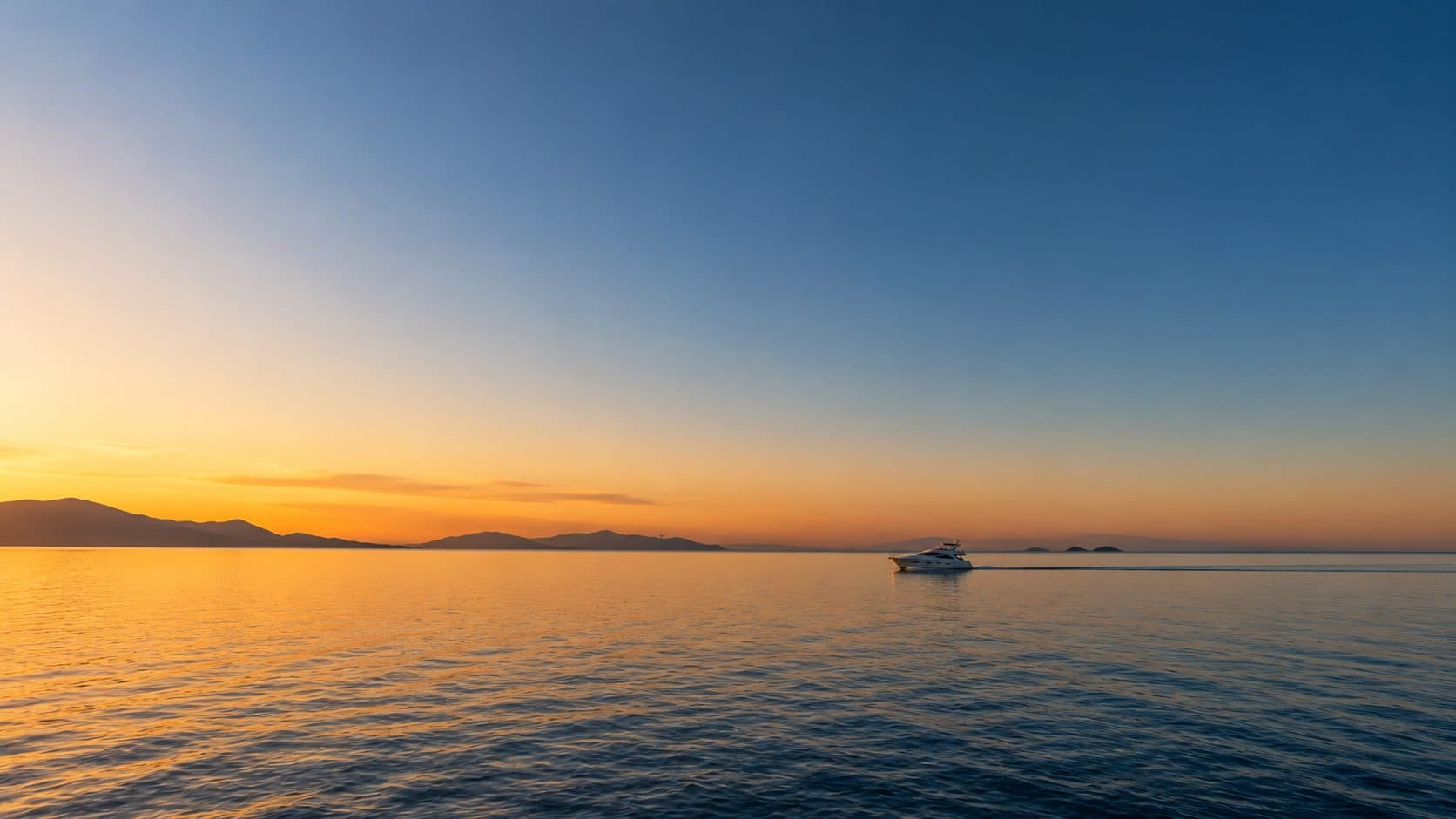 Gün batımında geniş deniz manzarası ve uzaktaki yat